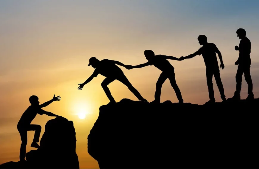 Plusieurs personnes aident une personne seule à escalader un rocher.